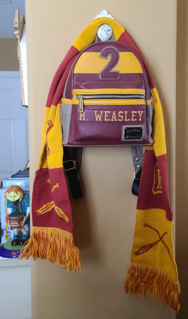 A gryffindor scarf and mini backpack hanging on a hook